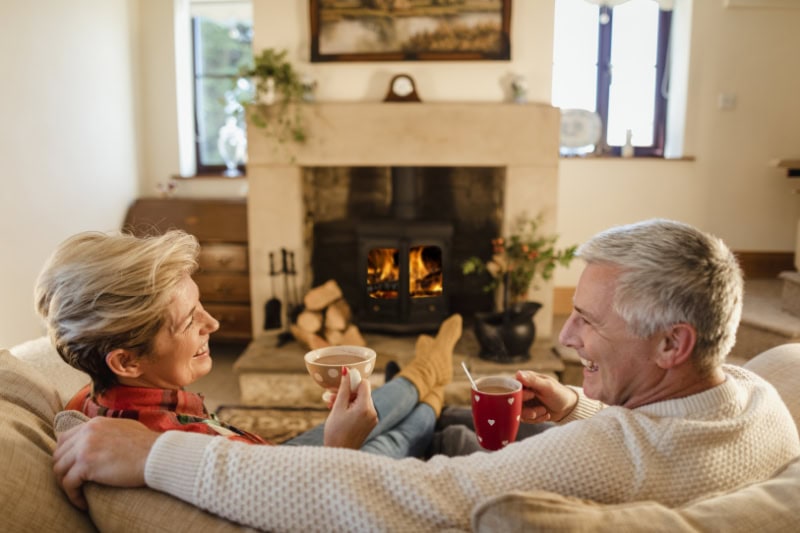 couple sitting in front of a fireplace drinking hot chocolate.